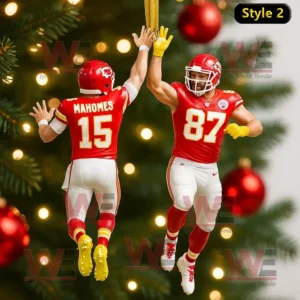 Two Kansas City Chiefs football players in red uniforms high fiving as Christmas ornaments on a tree.