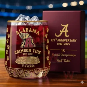 A clear depiction of an Alabama Crimson Tide glass with ice and decorative elements beside a commemorative box in an illuminated venue!