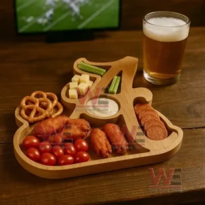 A wooden tray shaped with multiple compartments is filled with assorted snacks beside a glass of beer on a wooden surface with a blurred television in the background!