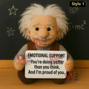 A soft handmade crochet doll with white hair holding a sign of encouragement on a classroom desk!