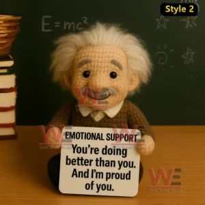 Albert Einstein Emotional Support Doll 3 A handmade crochet doll with white hair sitting by books and a chalkboard holding an encouraging message sign!