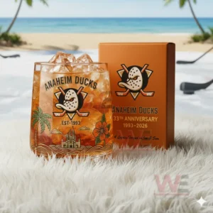 A glass with the Anaheim Ducks logo and tropical designs placed on white fur near the beach with an orange anniversary box in the background!