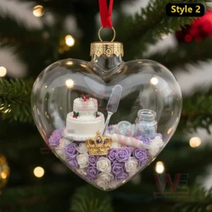 Alt text: A heart-shaped ornament with a miniature wedding cake, a cake server, and a crown, decorated with roses.