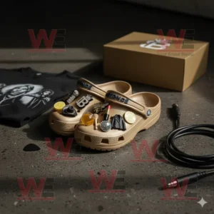 Beige Beyonce Crocs with themed charms placed near a t-shirt and golden box on the floor.