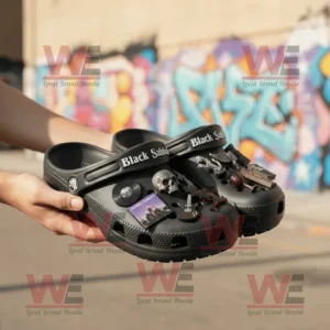 Black Sabbath Crocs Clogs with Charms 8 Person holding Black Sabbath Crocs with rock inspired charms in front of graffiti wall.