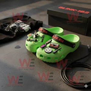 Blink 182 Crocs Clogs with Charms 6 Blink-182 green Crocs with charms beside a t-shirt and black box on the floor.