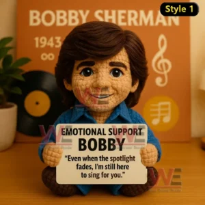 A handmade crochet doll with brown hair and a blue shirt holding an encouraging message sign in a music themed setting!