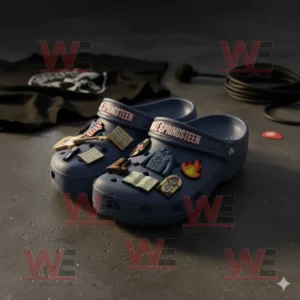 Blue Bruce Springsteen Crocs decorated with themed charms arranged on a dark stage surface near a coiled microphone cable and clothing item!