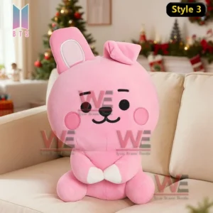 Yellow plush character with black ears sitting on a sofa with Christmas decorations behind it!