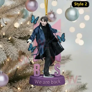 A Christmas ornament showing one person posing with butterfly decorations in front of a tree with holiday lights!