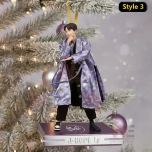 A Christmas ornament showing a person in a purple robe standing on a platform in front of a decorated tree!