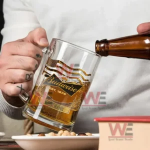 Budweiser Custom Beer Glasses 5 Hand holding Budweiser engraved mug while beer is being poured from a bottle into it.