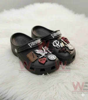 Black clogs resting on a white fluffy surface with raised music themed charms.
