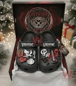 Open gift box showing black decorated clogs with raised charms and holiday decor around.``