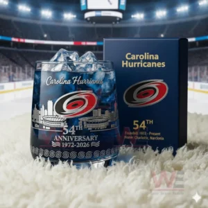 A Carolina Hurricanes glass with blue drink and ice placed on a white rug with the team anniversary box and hockey rink background!