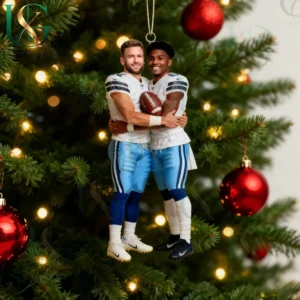 Football themed Christmas ornament showing two players in white and blue uniforms hugging with festive tree decorations around them!