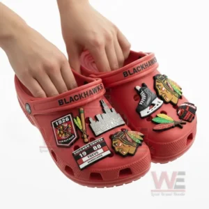 Chicago Blackhawks Crocs Crocband Clogs 6 Hands holding Chicago Blackhawks-themed Crocs with charms.