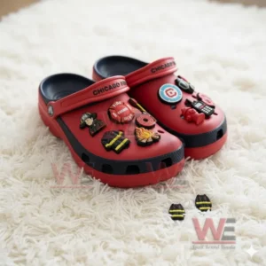Red clogs decorated with firefighter charms resting on a white rug!