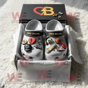 White Chris Brown themed Crocs displayed in packaging with colorful charms and the artist’s initials highlighted on black straps!