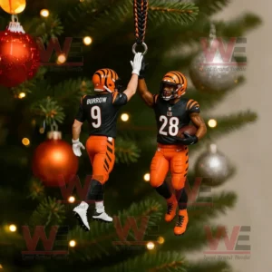 A Christmas ornament of two Bengals football players midair high fiving while hanging on a Christmas tree branch with red and silver baubles around!