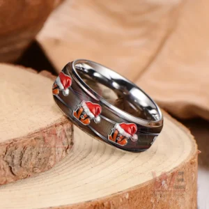 A close-up of a Cincinnati Bengals Christmas-themed ring, showcasing the festive logo on a silver tungsten band placed on a wooden surface.