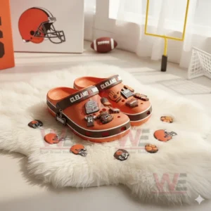 Orange Cleveland Browns clogs with various football charms displayed on a white furry rug near a window!