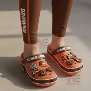 Cleveland Browns Crocs Crocband Clogs With Charms 8 Person wearing orange Cleveland Browns clogs with football charms on a concrete surface!