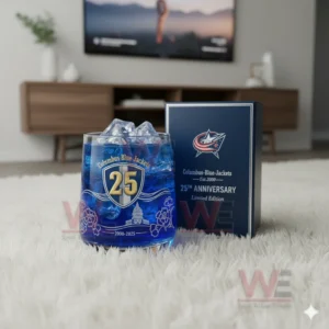 A blue Columbus Blue Jackets anniversary glass with ice placed beside a matching box on a white rug in a modern living room.