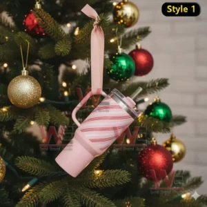 Pink tumbler ornament hanging on a Christmas tree among green branches and holiday decorations!