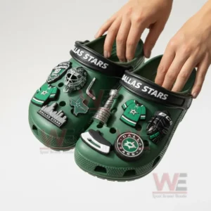 Hands holding Dallas Stars-themed Crocs with hockey-related charms.