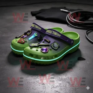 Green and purple Descendants Zombies Crocs with attached charms and glowing soles on a dark surface!