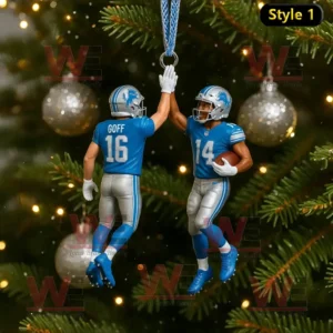 A Christmas ornament of two Detroit Lions football players giving a high five hanging on a decorated tree with silver and gold lights around!