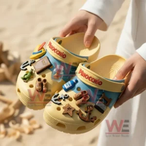 Alt text: Person holding Disney Pinocchio-themed crocs decorated with charms like a book, bottle, and anchor.
