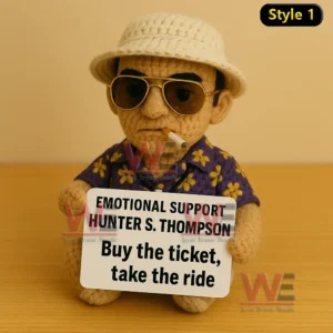 Crochet doll wearing purple flower shirt and sunglasses holding Emotional Support Hunter S Thompson sign with cigarette in mouth.