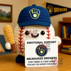 Crochet baseball doll wearing Brewers cap holding bat and Emotional Support Milwaukee Brewers sign on wooden table.