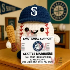 Crochet baseball doll wearing Padres cap holding bat and Emotional Support San Diego Padres sign on desk with team banners.