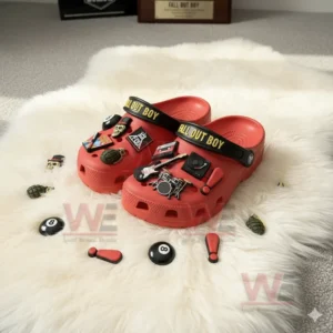 Red Crocs covered with various Fall Out Boy inspired charms such as a skull, guitar, grenade, and drum set displayed on a fluffy white rug!