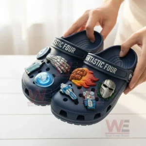 Close up of navy blue Fantastic Four Crocs held by hands showing charms of fire, metal fist, mask, and advanced vehicles!