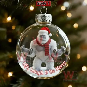 Clear ornament with a yeti lifting dumbbells wearing a Santa hat hanging on a lit Christmas tree!