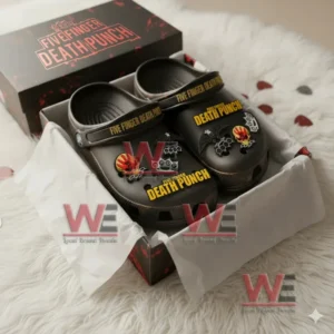 Black Five Finger Death Punch Crocs with yellow logo and themed charms placed in an open box on a soft rug.