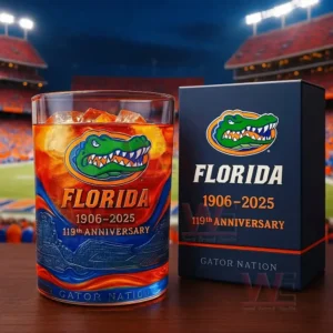 A brightly colored anniversary glass and its matching box sit on a table with a football stadium in the background!