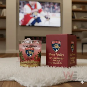 Florida Panthers anniversary glass with ice next to its box on a rug with a hockey game playing on TV in the background.