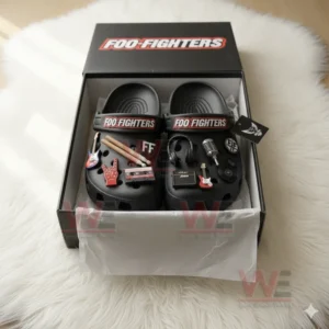 Black Crocs with Foo Fighters straps and decorative charms including instruments and band icons presented in their official packaging on a fluffy white surface!