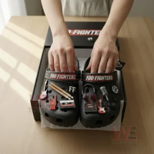 Close up of hands taking black Crocs decorated with Foo Fighters branding and rock music charms out of a stylish black box!