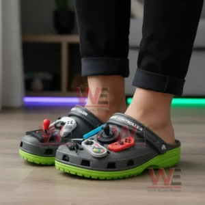 Person wearing gray and green clogs decorated with gaming controller themed charms indoors!