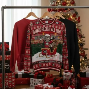 Alt text: Georgia Bulldogs Christmas sweaters hanging on a display rack with a Christmas tree and gifts in the background.