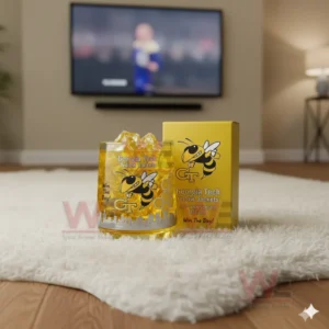 Georgia Tech Yellow Jackets whiskey glass with yellow ice and a commemorative box, resting on the floor while a football game plays on the TV.
