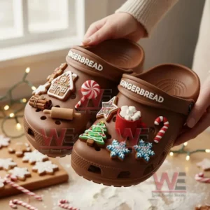 Hands lifting brown gingerbread themed clogs decorated with candy cane cookies and holiday charms!