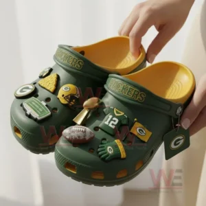 Green and yellow Green Bay Packers clogs with football charms held by a person indoors!