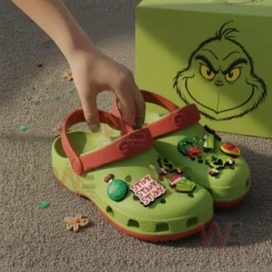 Green Grinch themed clogs with holiday charms held by a person on a carpeted floor!